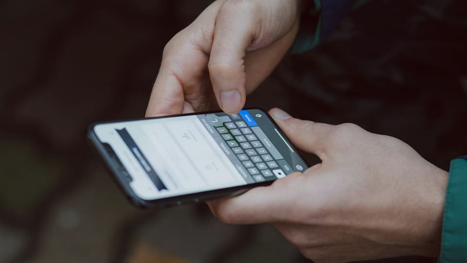 Two hands typing a search into a smartphone