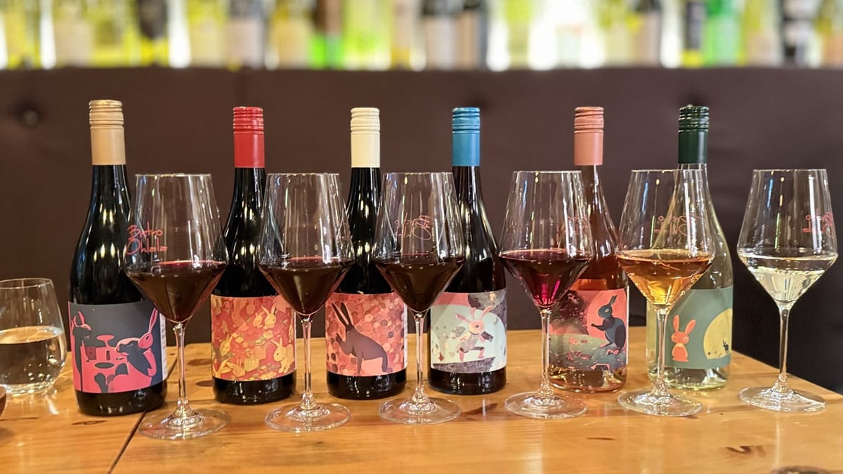 A line-up of The Angry Rabbit wines with filled glasses on a bar